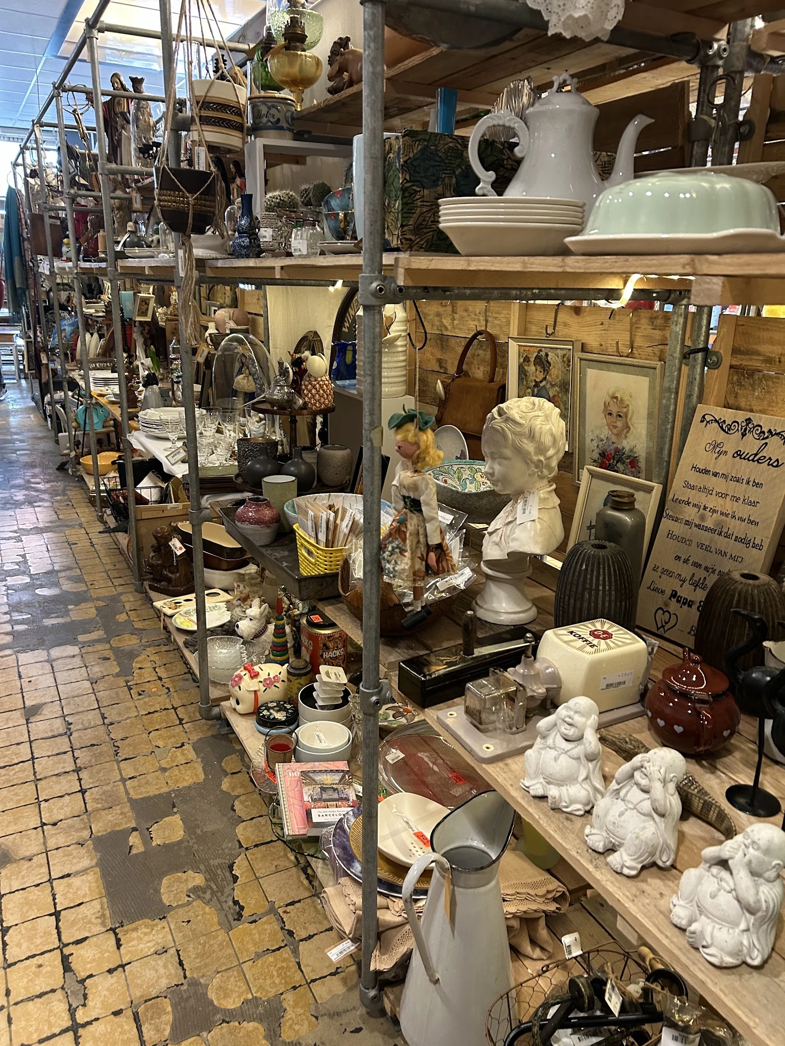 Diverse tweedehands items uitgestald in kringloopwinkel, waaronder beeldjes, serviesgoed, huishoudelijke artikelen en decorat