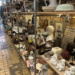 Diverse tweedehands items uitgestald in kringloopwinkel, waaronder beeldjes, serviesgoed, huishoudelijke artikelen en decorat
