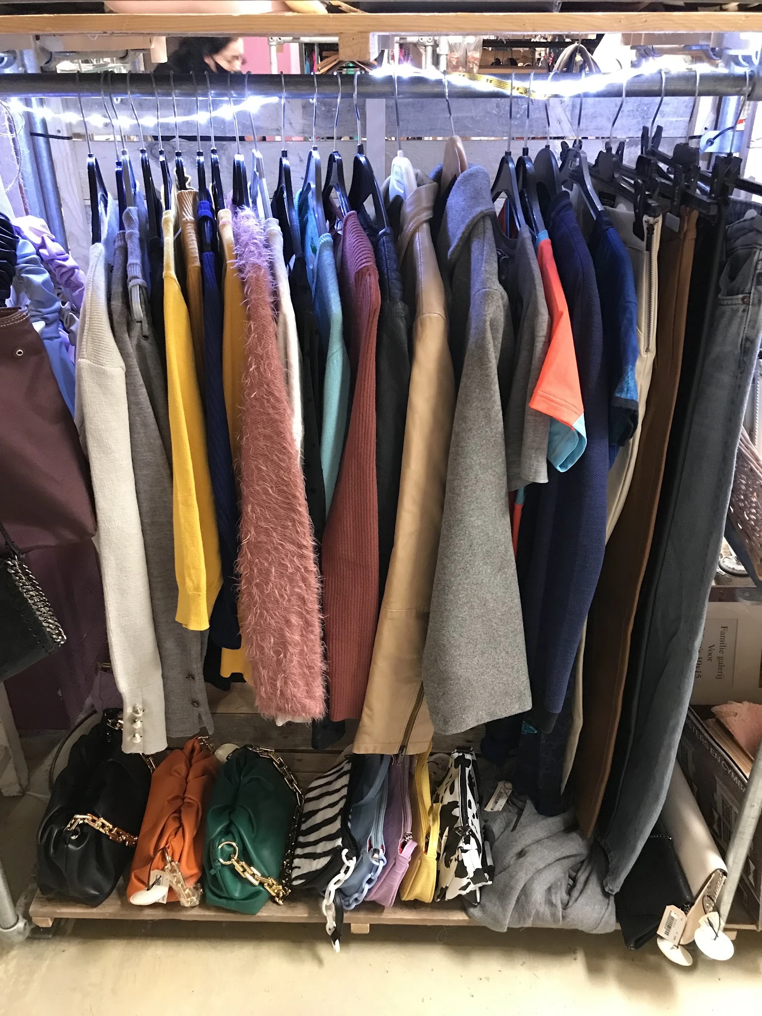 Rekken met tweedehands kleding in verschillende kleuren en materialen