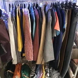 Rekken met tweedehands kleding in verschillende kleuren en materialen