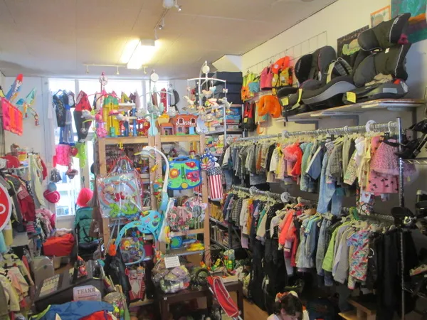 Winkelbinnenruimte met rekken vol kinderkleding, speelgoed en accessoires tegen de wanden