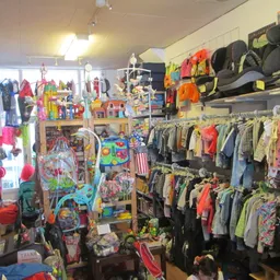 Winkelvloer met rekken vol kinderkleding, speelgoed en artikelen, breed overzicht van het assortiment