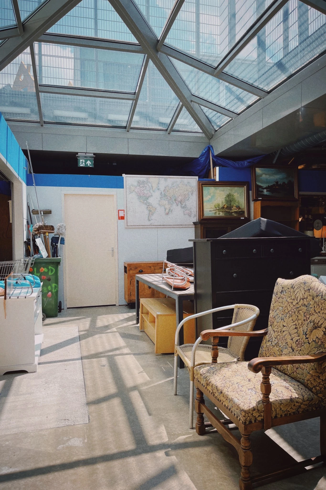 Winkelvloer met meubels, stoelen, een zwarte kast en uitgestalde spullen in een kringloopwinkel