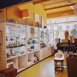 Winkelinterieur met glazen vitrinekasten vol decoratiespullen en antiekartikelen, piano op de achtergrond