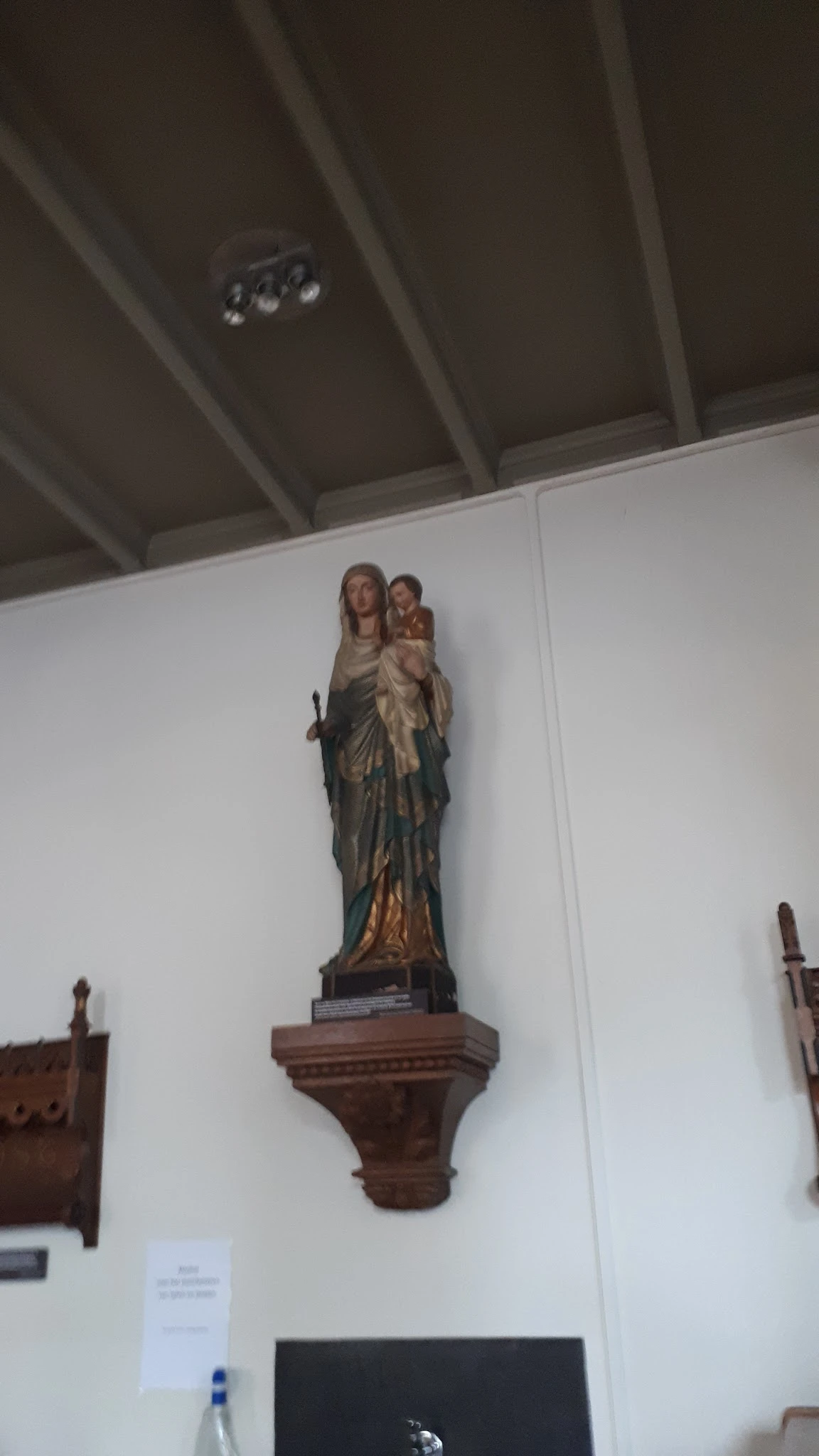 Gekleurde houten beeldengroep van Maria met kind tegen witte wand