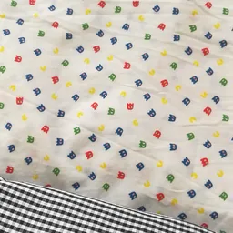 Stof met kindermotief in blauw, rood, groen en geel op een wit achtergrond