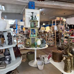 Kringloopwinkel interieur met houten stellingen, diverse huishoudartikelen, lampen, servies en decoratieve items