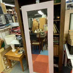 Kringloopwinkelinterieur met diverse meubels, boeken, elektronische apparaten en huishoudspullen verspreid over stellingen en