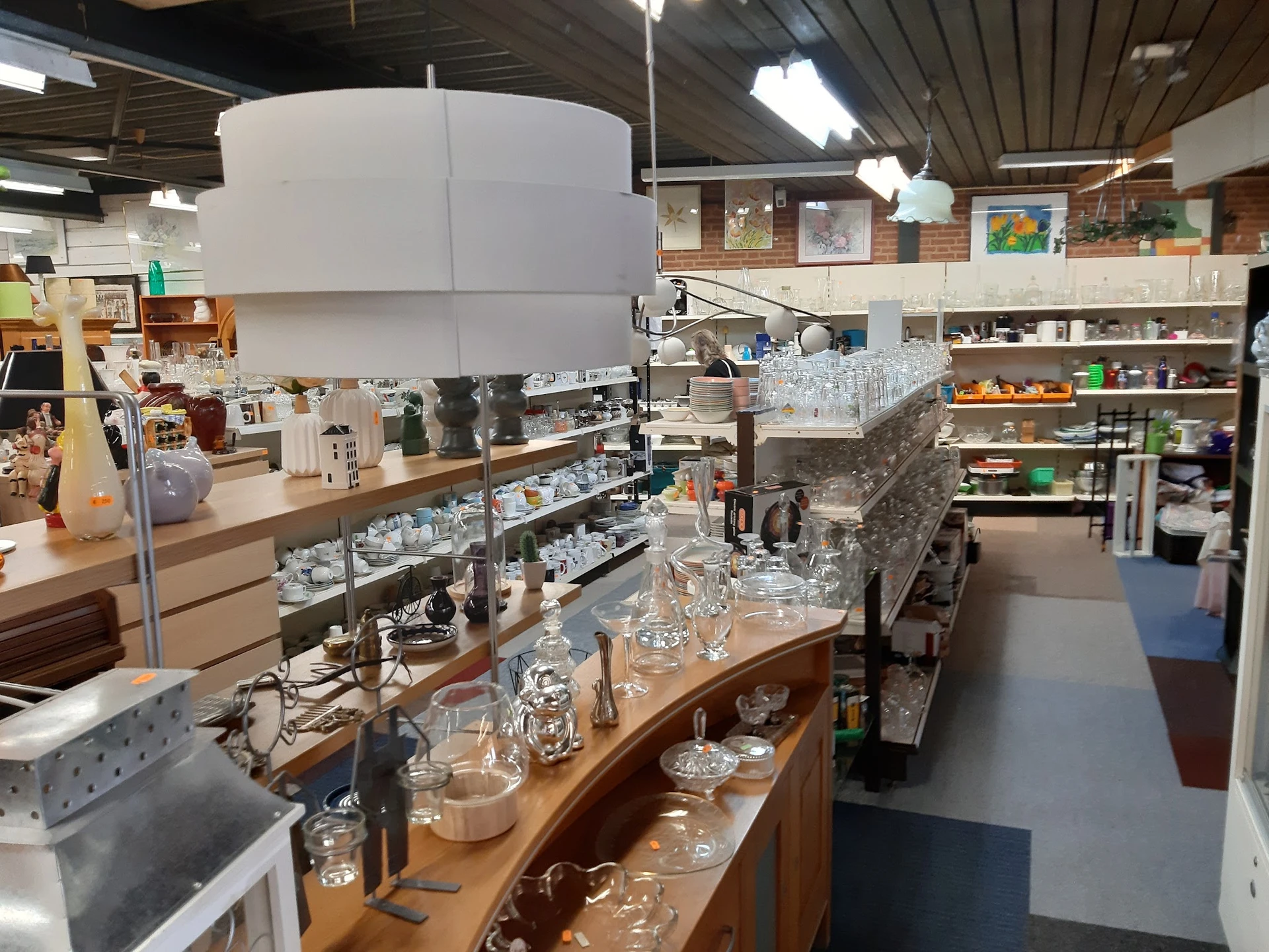 Glazen vazen, potten en servies uitgestald op houten toonbanken in de winkel