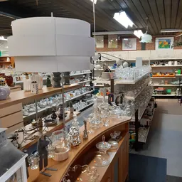 Glazen vazen, potten en servies uitgestald op houten toonbanken in de winkel