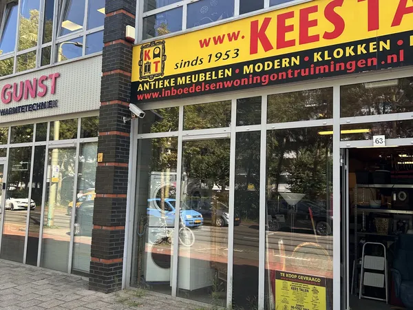 Winkelgevel met gele grijze letters en grote ramen, drukke straat met reflecties