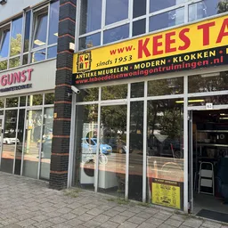 Winkelgevel met gele grijze letters en grote ramen, drukke straat met reflecties