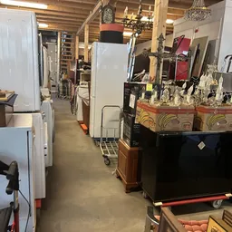 Winkelinterieur met stellingen, kastjes en diverse tweedehands spullen langs de zijkanten