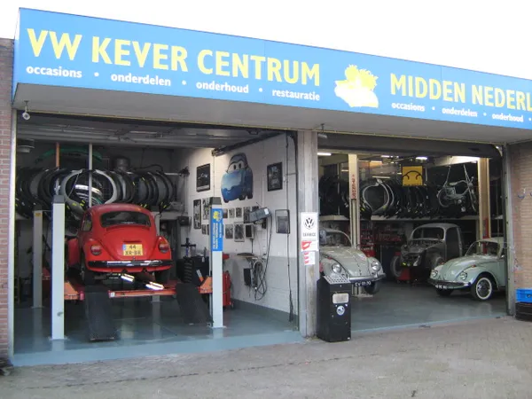 Voorgevel van VW Kever Centrum met rode en grijze vintage Volkswagen Kever auto's in de showroom
