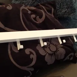 Close-up van een witte gordijnroede met ringen op donkerpaarse stof met bloemmotief