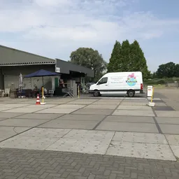Bedrijfsbus van Kiekeboe geparkeerd op het terrein voor de winkelunit