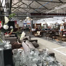 Ruim interieur van kringloopwinkel met meubels, tafels, stoelen en diverse spullen uitgestald