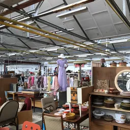 Winkelvloer van kringloopwinkel met rekken kleding, meubilair, servies en diverse tweedehands artikelen