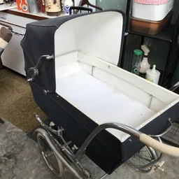 Zwarte kinderwagen met witte binnenkant, open uitgestald in de winkel