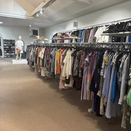 Winkelvloer met rekken vol tweedehands kleding, mannequin en artikel-display in kringloopwinkel