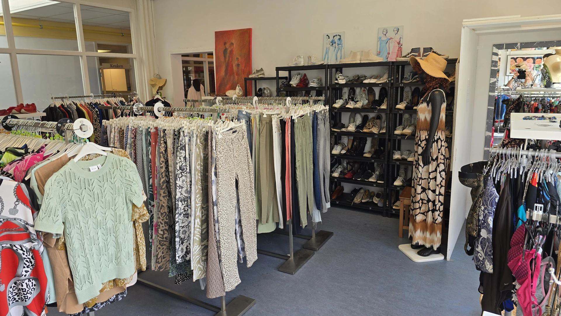 Winkelinterieur met kledingrekken, schoenenkasten en tweedehands kleding uit verschillende categorieën