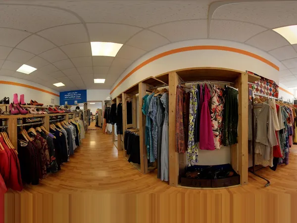 Winkelvloer met kledingrekken en houten kledingkasten vol tweedehands kleding