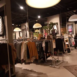Interieur van kledingboetiek met kledingrekken, hangende lampen en uitgestalde kleding