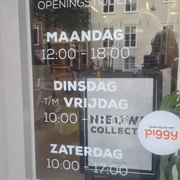 Openingstijden op een winkelruit: maandag 12:00-18:00, dinsdag t/m vrijdag 10:00-18:00, zaterdag gesloten. Piggy-logo zichtba