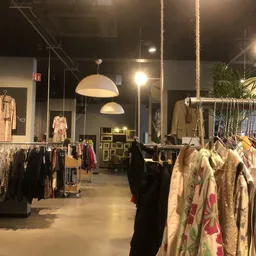 Ruim winkelinterieur met kledingrekken, hangende kleding en moderne verlichting