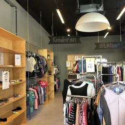 Winkelinterieur met houten stellingen vol kinderkleding, rekken met kleding en verlichtingselementen