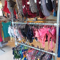 Rekken met tweedehands kleding, vooral roze en rode items, onderbroeken en lingerie