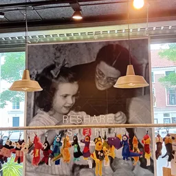 Winkelinterieur met groot vintage portret aan wand, hangende gele lampen en decoratieve figuren aan een rail