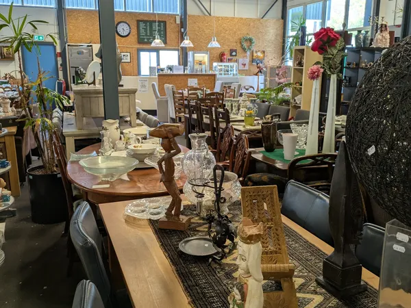 Winkelvloer met diverse meubels, tafels, stoelen, serviesgoed en decoratieve items uitgestald