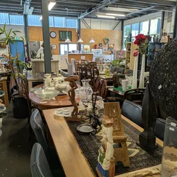Winkelvloer met diverse meubels, tafels, stoelen, serviesgoed en decoratieve items uitgestald
