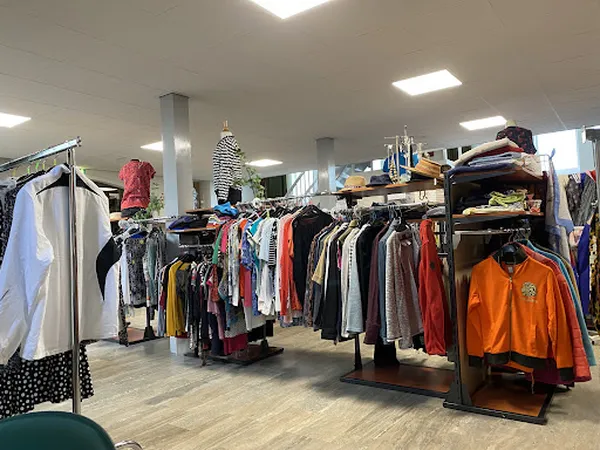 Winkelvloer met kledingrekken vol tweedehands kleding in verschillende kleuren