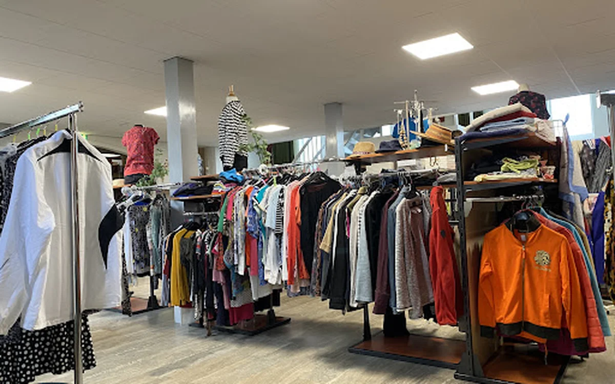 Winkelvloer met kledingrekken vol tweedehands kleding in verschillende kleuren