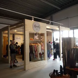 Winkelinterieur met houten stellingen vol kleding, klanten aan het winkelen, moderne kringloopwinkel