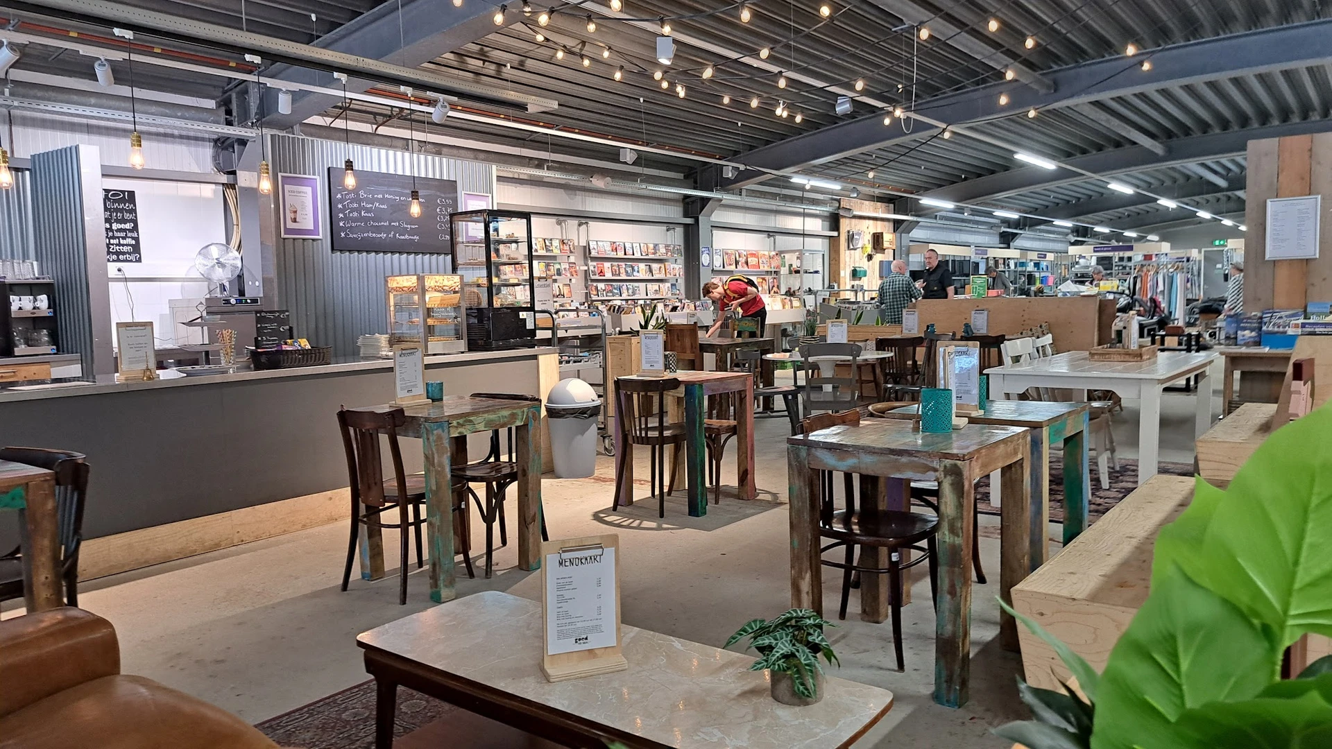 Winkelvloer met tafels, stoelen en diverse meubels in een kringloopwinkel