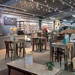 Winkelvloer met tafels, stoelen en diverse meubels in een kringloopwinkel