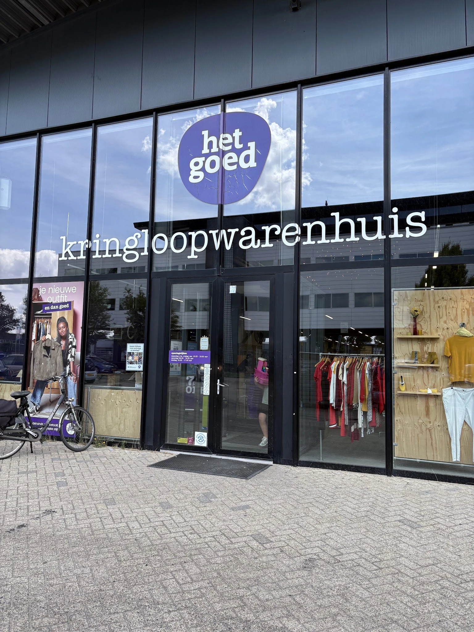 Gevel van kringloopwinkel met grote ramen, zwarte kozijnen en het logo 'het goed' bovenaan. Winkelnaam 'kringloopwarenhuis' i