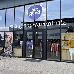 Gevel van kringloopwinkel met grote ramen, zwarte kozijnen en het logo 'het goed' bovenaan. Winkelnaam 'kringloopwarenhuis' i