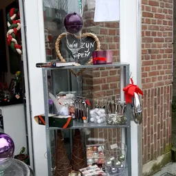 Vitrinekast met decoratieve items en kerstversiering in een tweedehandswinkel