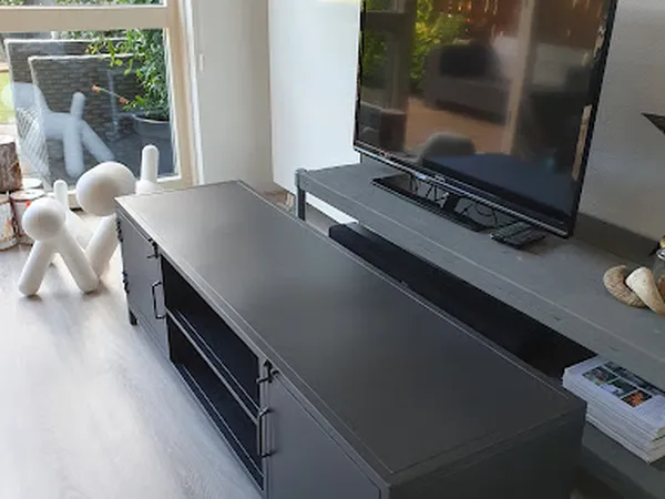 Woonkamer interieur met tv op standaard, witte decoratieve beelden en raam met uitzicht op tuin