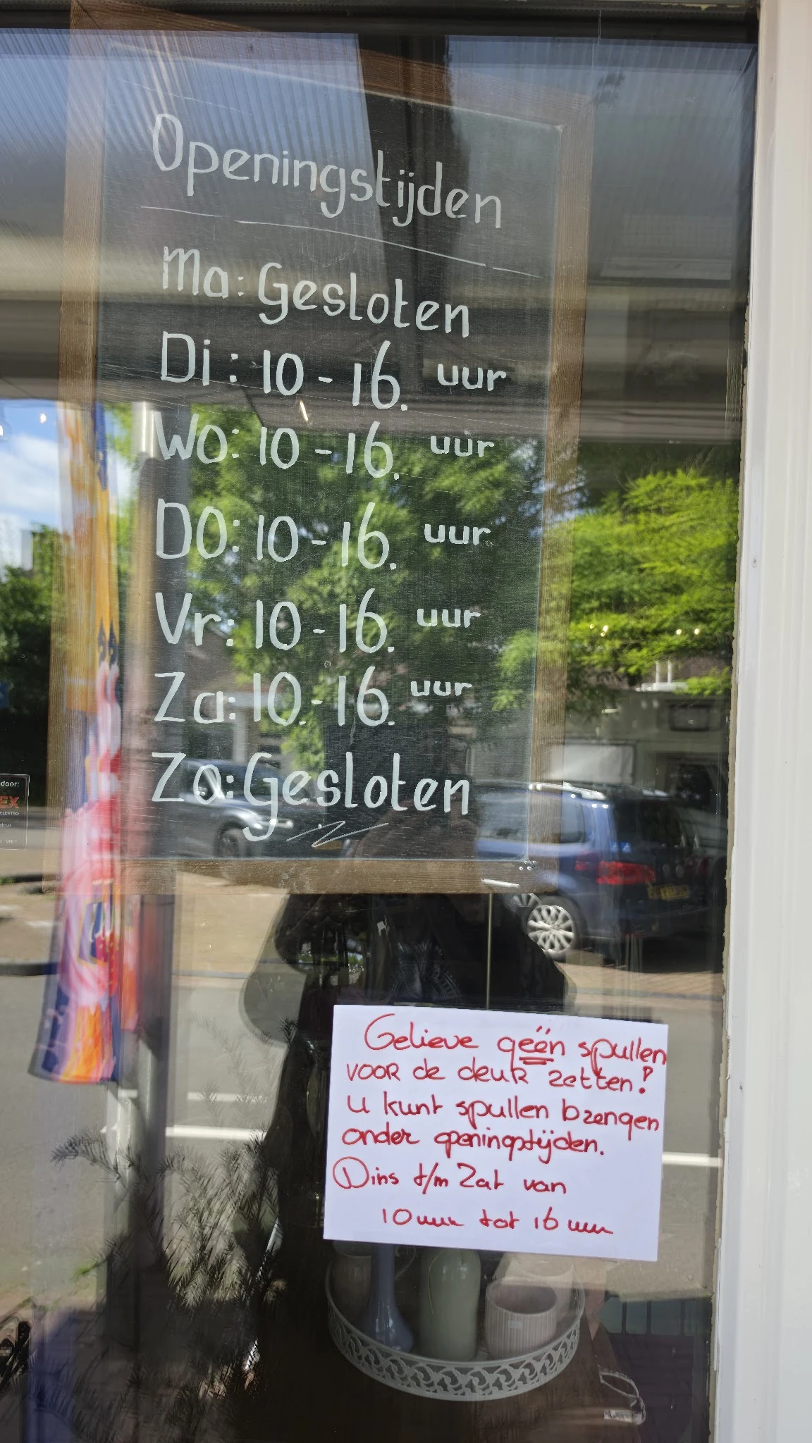 Openingstijden en sluitingsinformatie op een winkelruit geschreven: maandag tot zaterdag 10-16 uur, zondag gesloten