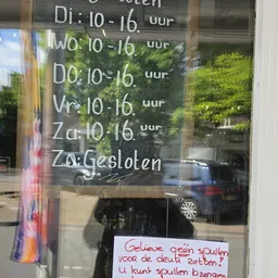 Openingstijden en sluitingsinformatie op een winkelruit geschreven: maandag tot zaterdag 10-16 uur, zondag gesloten