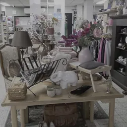 Uitgestalde meubels en decoratie-items in een kringloopwinkel, waaronder stoelen, lampen, vazen en bloemen