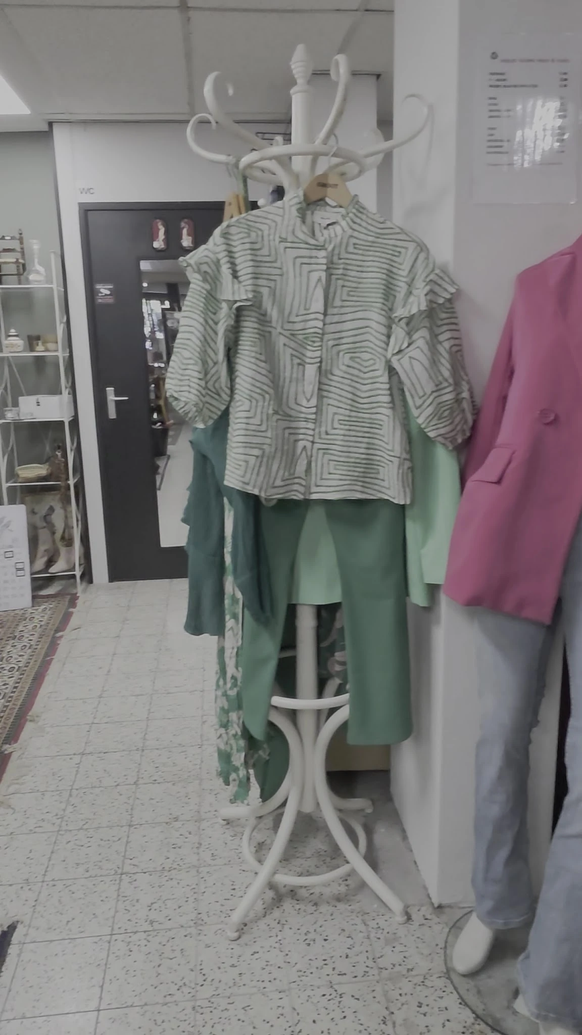 Tweedehands kleding op hangers: een gestreept shirt en groene en roze jassen