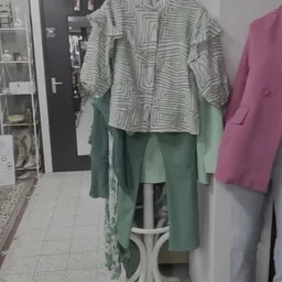 Tweedehands kleding op hangers: een gestreept shirt en groene en roze jassen
