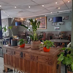Gezellig ingerichte koffiehuis met houten kastmeubel, potplanten, verlichting en zithoeken op de achtergrond