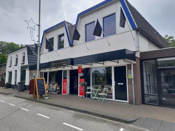 Witte winkelgevel met blauwe accenten en grote ramen, met terras en rode decoratie aan de voorkant